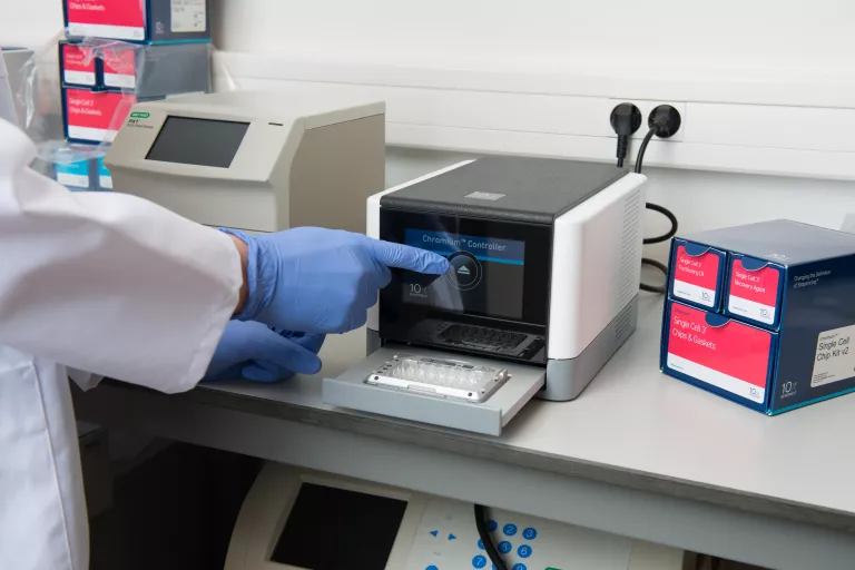 10x Genomics chromium instrument being used by a scientist in a lab coat and gloves