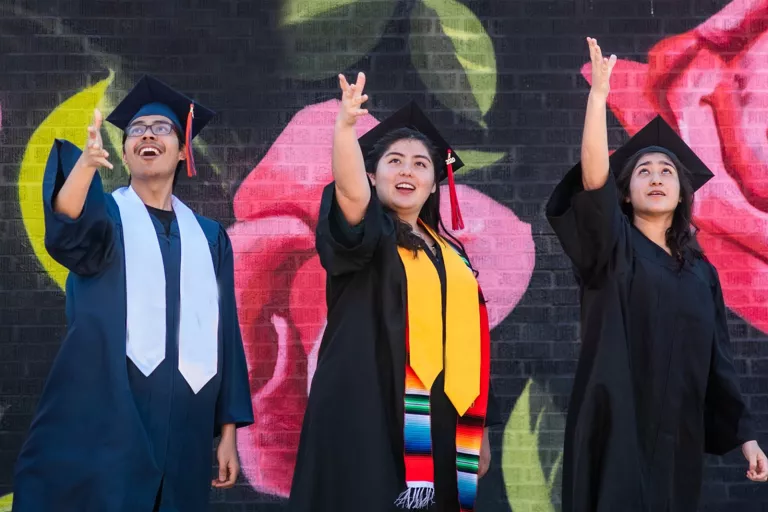Stock image of three students graduating in graduation attire